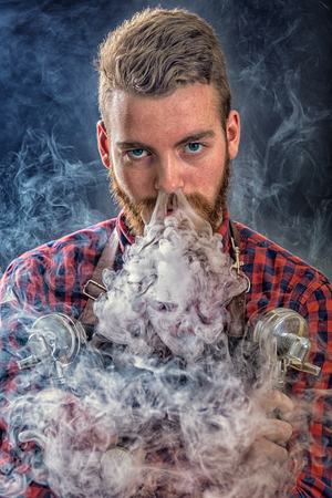 Coffe man. Barista with two portafilters. Hipster man with the release of smoke nose.の写真素材