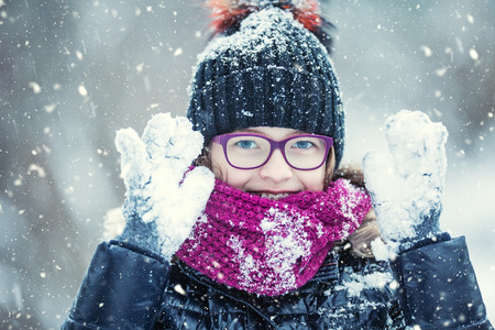 Beauty Winter happy Girl Blowing Snow in frosty winter park or outdoors. Girl and winter cold weather.の写真素材