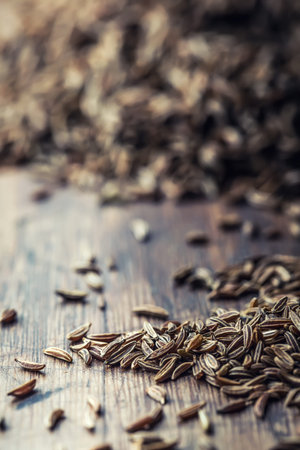 Cumin.Caraway seeds on wooden table. Cumin in vintage bronze bowl and spoon.