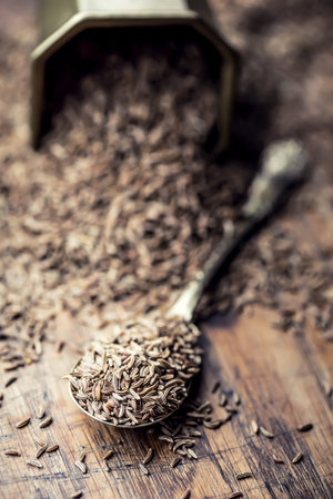 Cumin.Caraway seeds on wooden table. Cumin in vintage bronze bowl and spoon.