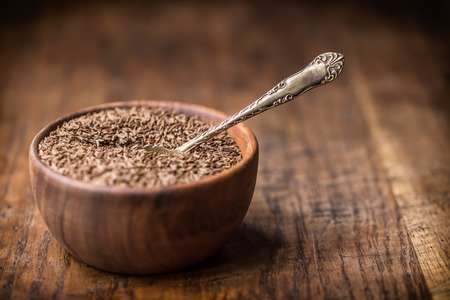 Cumin.Caraway seeds on wooden table. Cumin in vintage wooden bowl and vintage spoon.の写真素材