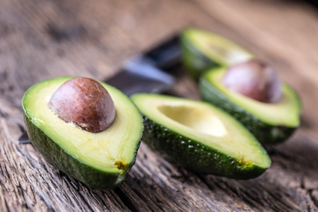 Avocado. Cut avocado on a oak wood background table. Selective focus.の写真素材