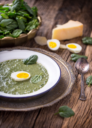 Spinach soup. Portion spinach soup with egg and cheese parmesan in retro style.の写真素材
