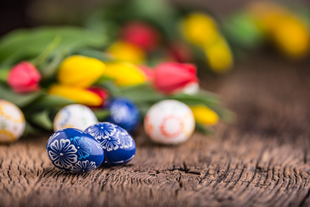 Easter. Hand made easter eggs and spring tulips on old wooden table.の写真素材