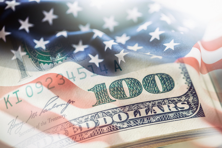 USA flag and American dollars. American flag blowing in the  wind and 100 dollars banknotes in the background.の写真素材