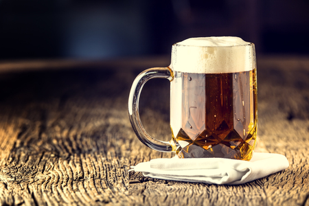 Beer. Draft golden beer in glass jar. Draft ale with froth on top. Cold beer on very old oak board.の写真素材