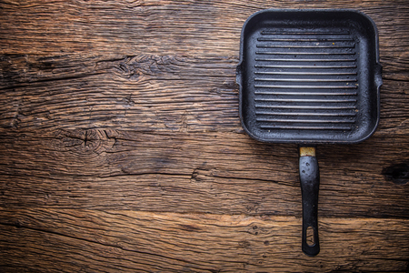 Dirty grill pan after frequent grilling. Grill pan on wooden board.の写真素材