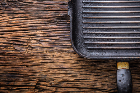 Dirty grill pan after frequent grilling. Grill pan on wooden board.の写真素材