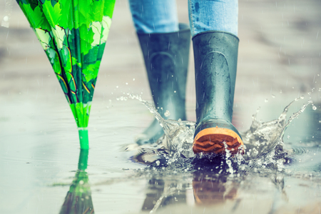 Girl in rubber boots outdoors in rainy day.の写真素材