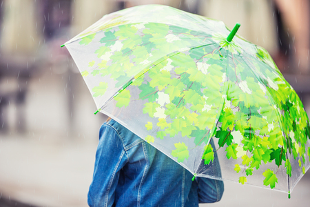 Portrait of beautiful young pre-teen girl with umbrella under rain.の写真素材