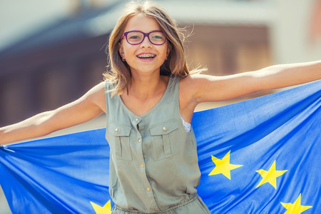 EU Flag. Cute happy girl with the flag of the European Union. Young teenage girl waving with the European Union flag in the city.の写真素材