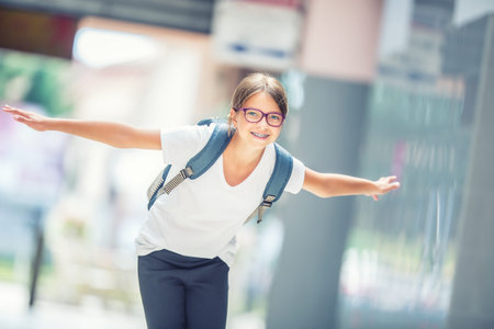 Schoolgirl with bag, backpack. Portrait of modern happy teen school girl with bag backpack. Girl with dental braces and glasses.の写真素材