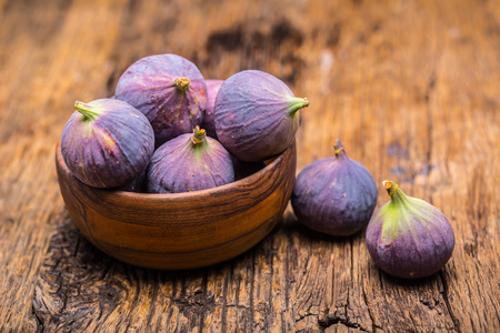 Figs. A few figs in a bowl on an old wooden background.の写真素材