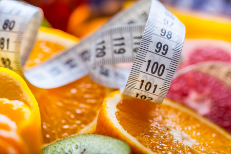 Measure tape and fresh citrus fruit orange lemon tangerine lime lemon and grapefruit.の写真素材