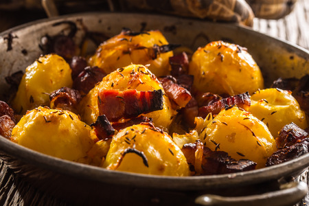 Potatoes. Roasted potatoes with bacon onion and sausages on old oak table.の写真素材