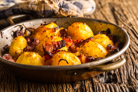 Potatoes. Roasted potatoes with bacon onion and sausages on old oak table.の写真素材