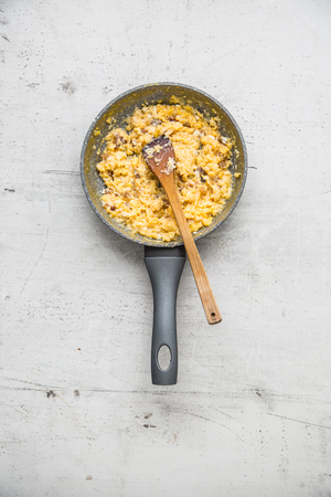 Ham and eggs. Scrambled eggs with bacon in ceramic pan.の写真素材