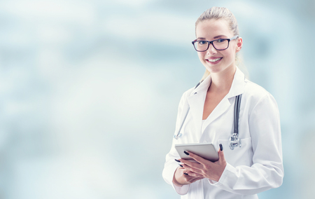 Young doctor woman smile face with tablet stethoscope and white coat.の写真素材