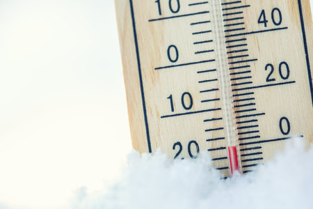 Thermometer on snow shows low temperatures under zero. Low temperatures in degrees Celsius and...