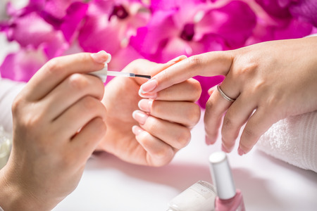 Manicure specialist painting woman gel nail. Art - French manicure.の写真素材
