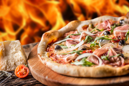 Pizza. Tasty fresh italian pizza served on old wooden table. Flames in the background.の写真素材