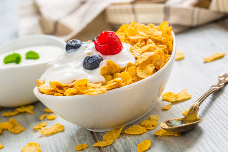 Cornflakes. Dish of cornflakes with yogurt blueberries and raspberries on kitchen table.