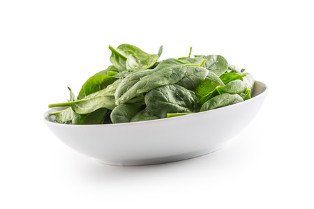 Spinach. Fresh baby spinach leaves in plate isolated on white.の写真素材