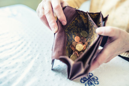 Pensioner woman holding in hands wallet with euro coins.