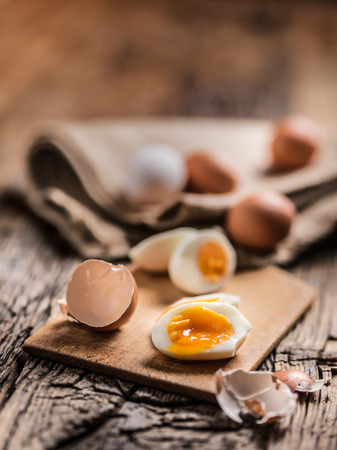 Close-up boiled or raw chicken eggs on wooden board.の写真素材