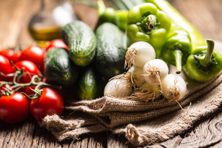 Fresh vegetable onion cucumber pepper and tomatoes on rustic oak table.の写真素材