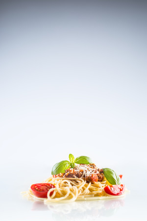 Spaghetti bolognese basil tomatoes and parmesan cheese on white background.の写真素材