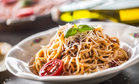 Spaghetti bolognese with ingredients basil tomatoesparmesan cheese and olive oil.の写真素材