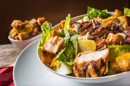 Delicious salad caesar with grilled chicken breast croutons eggs bacon parmesan cheese and  lettuce with dressing.の写真素材