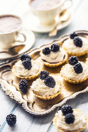 Mini tartlets with blackberries whipped cream and coffee.の写真素材
