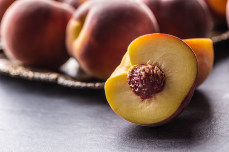 A group a ripe peaches in rustic bowl.の写真素材