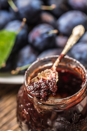 Close-up spoon from plum jam and fresh plums in the background.の写真素材