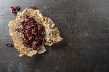 A pile of dried beef jerky pieces on paper and cutting board.の写真素材