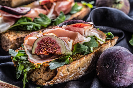 Sandwich with figs prosciutto spinach arugula and cheese dip.の写真素材