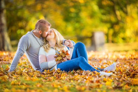 A loving couple in an autumn park lies on the leaves.の写真素材