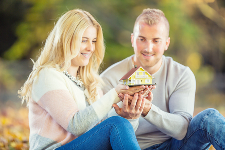 Young loving couple holding small model house.の写真素材