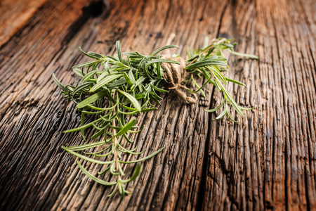 Close-up fresh rosemary on rustic oak board.の写真素材