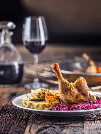 Portion of roast duck leg red cabbage homemade dumplings on plate and red wine on the background.の写真素材