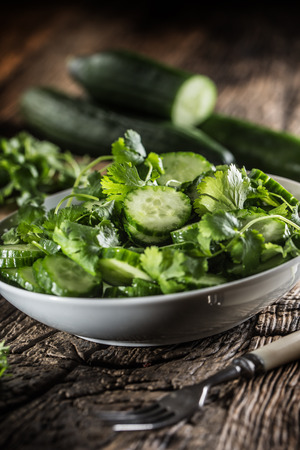 Sliced cucumber on a plate with parsley herb on rustic oak wood.の写真素材