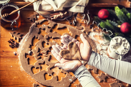 Christmas baking and gingerbread heart in woman hands.
