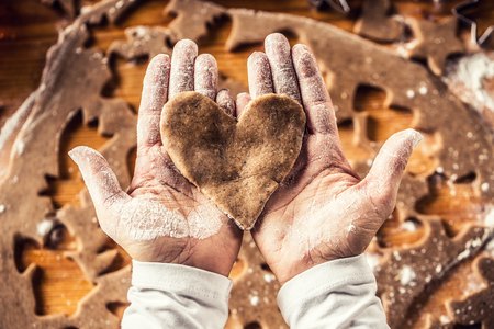 Christmas baking and gingerbread heart in woman hands.の写真素材