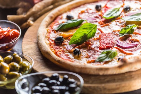 Pizza diavolo traditional italian meal from spicy salami peperoni chili onion olives and basil.の写真素材