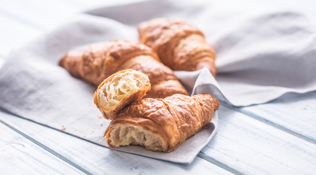Fresh buttery croissants on kitchen napkin and wooden table.の写真素材