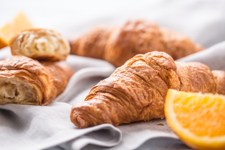 Fresh buttery croisants with sweet oranges on kitchen napkin.の写真素材