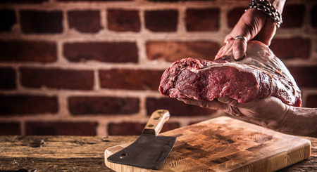 Butcher man hands holding raw beef steak in butchery.の写真素材