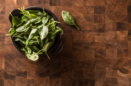Top of view fresh baby spinach leaves in bowl on butcher board.の写真素材